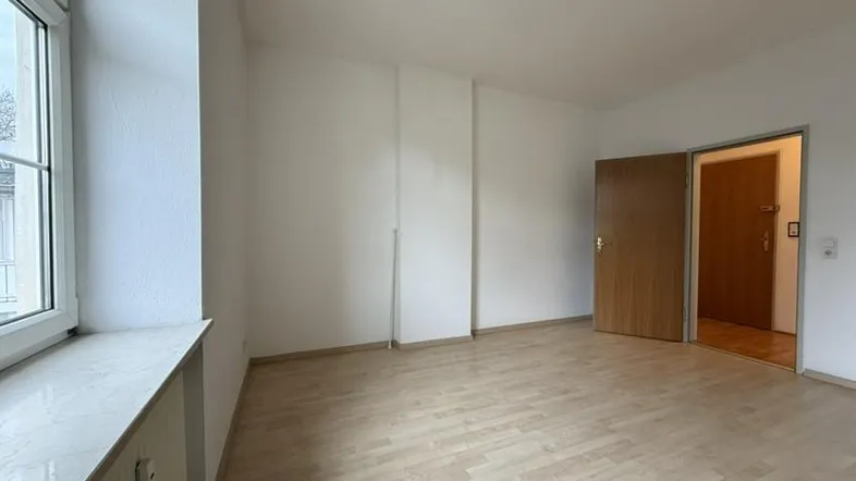 Helles Zimmer mit hellem Holzfußboden und weiß gestrichenen Wänden, bereit zur individuellen Gestaltung.