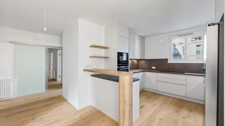 Moderne offene Küche mit Holzboden, Frühstücksbar und integrierten Geräten.