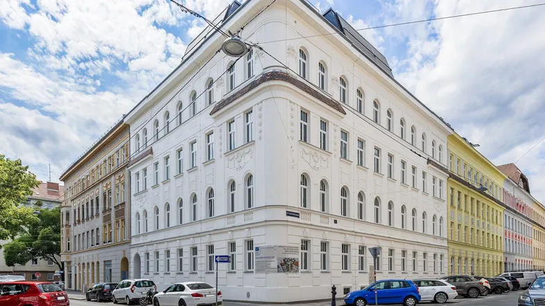 Historisches Eckgebäude mit klassischer Architektur und vielen Fenstern in städtischer Umgebung.