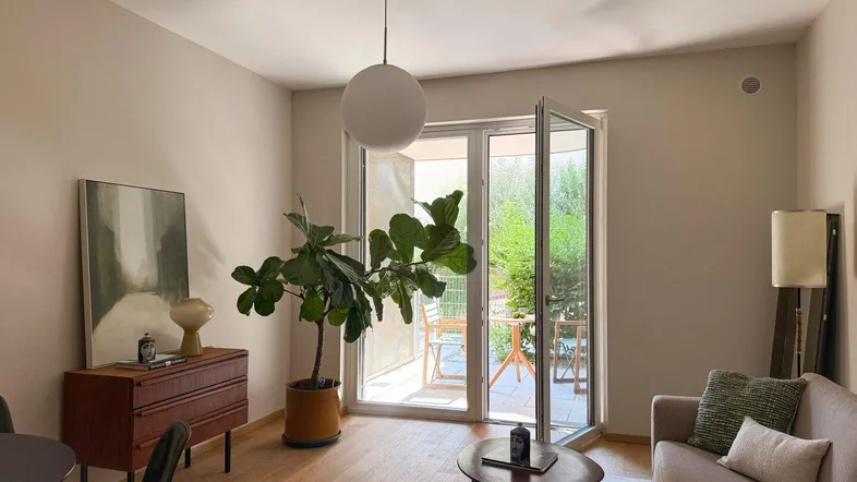 Helles Wohnzimmer mit Holzboden, modernen Möbeln und direktem Zugang zu einer Außenterrasse.