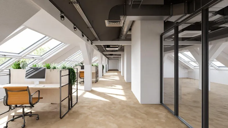 Modernes Großraumbüro im Dachgeschoss mit vielen Dachfenstern, industrieller Decke und ergonomischen Arbeitsplätzen.