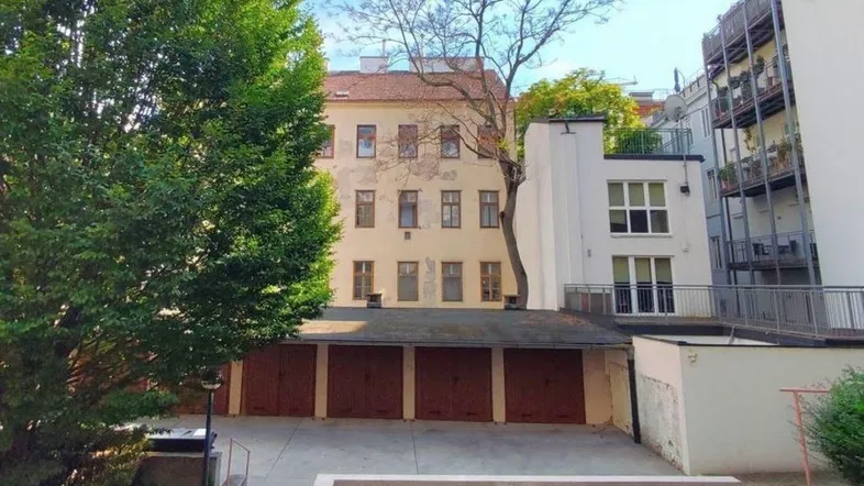 Ansicht eines Hinterhofs mit Garagenreihe, einem älteren Wohngebäude und einem modernen Anbau.