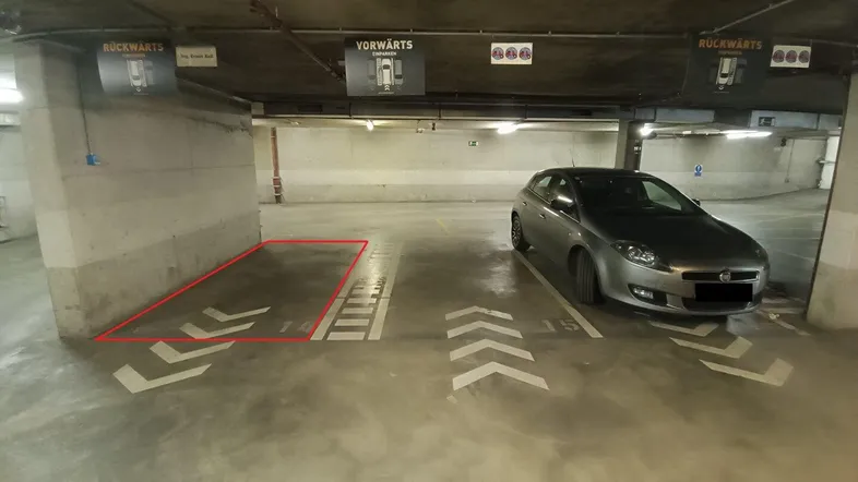 Tiefgaragenstellplatz Nummer 14, deutlich markiert und bereit zur Nutzung, mit einem geparkten Auto daneben.