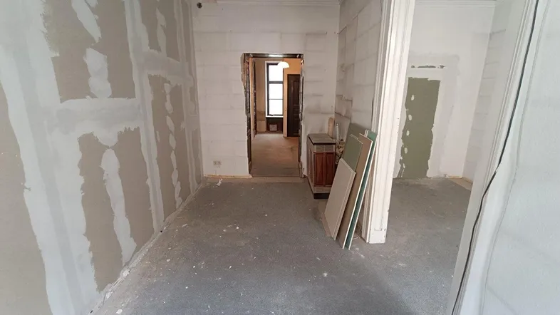 Unfertiger Innenraum mit Trockenbauwänden und Rohbetonboden, bereit für den Ausbau.