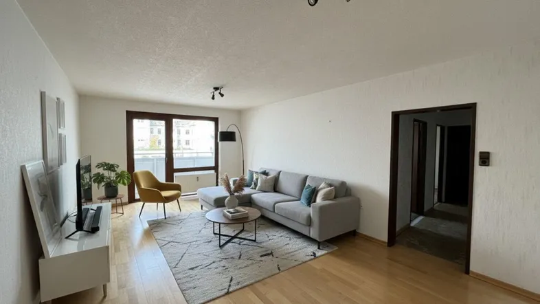 Helles Wohnzimmer mit modernem Sofa, Teppich und Zugang zum Balkon.