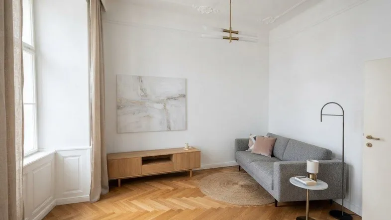 Helles Wohnzimmer mit Fischgrätparkett, Stuckdecke und moderner Einrichtung in einem Altbau.