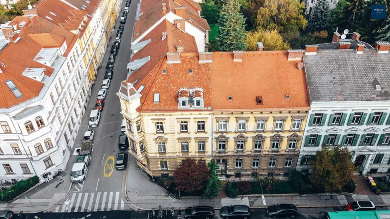 Luftaufnahme eines historischen Wohngebäudes mit rotem Ziegeldach und umliegenden Straßen.