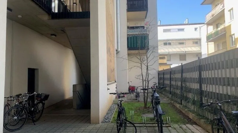 Außenbereich eines Mehrfamilienhauses mit Fahrradabstellplätzen und Zugang zum Treppenhaus.