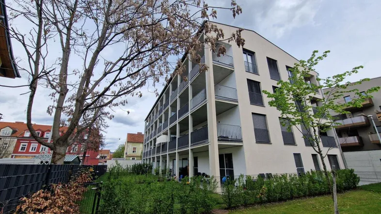 Modernes Mehrfamilienhaus mit mehreren Balkonen und gepflegter Grünfläche.