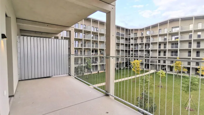Geräumiger Balkon mit Blick auf den begrünten Innenhof und die moderne Wohnanlage.
