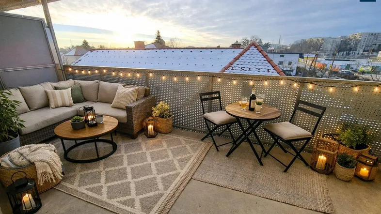 Gemütlicher Balkon mit Sitzgelegenheiten, Teppichen und Lichterkette für entspannte Abende.