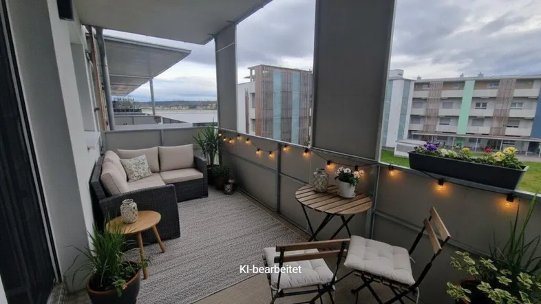 Gemütlicher Balkon mit modernen Sitzgelegenheiten, Pflanzen und Lichterkette, bietet einen weiten Blick auf die Umgebung und Wasser.