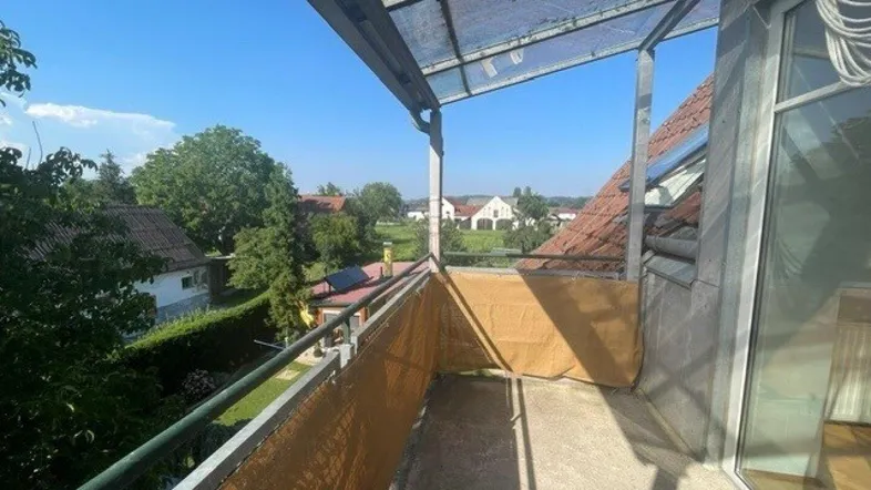 Heller Balkon mit Überdachung und weitem Blick über die Dächer und ins Grüne.