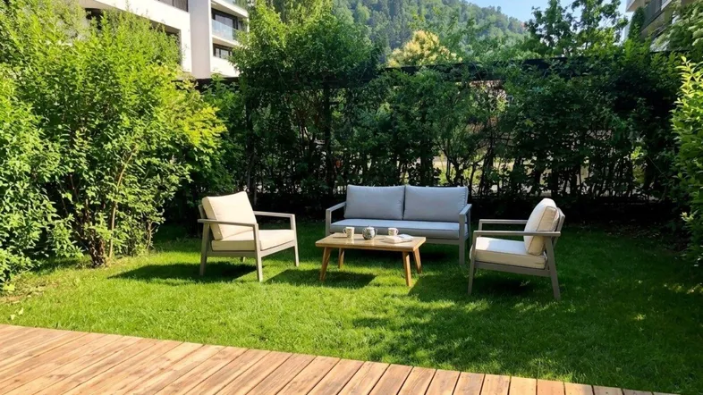 Gemütlicher Gartenbereich mit Holzterrasse und bequemen Sitzmöbeln, umgeben von grüner Hecke.
