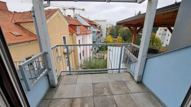 Geräumiger Balkon mit Fliesenboden und Blick auf die umliegenden Gebäude und Kräne.