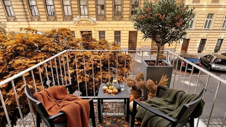 Gemütlicher Balkon mit herbstlicher Dekoration und Blick auf die gegenüberliegende Altbaufassade.