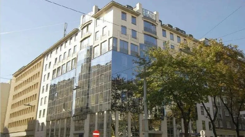 Gebäude mit einer Kombination aus traditioneller Fassade und moderner Glasfront in städtischer Umgebung.