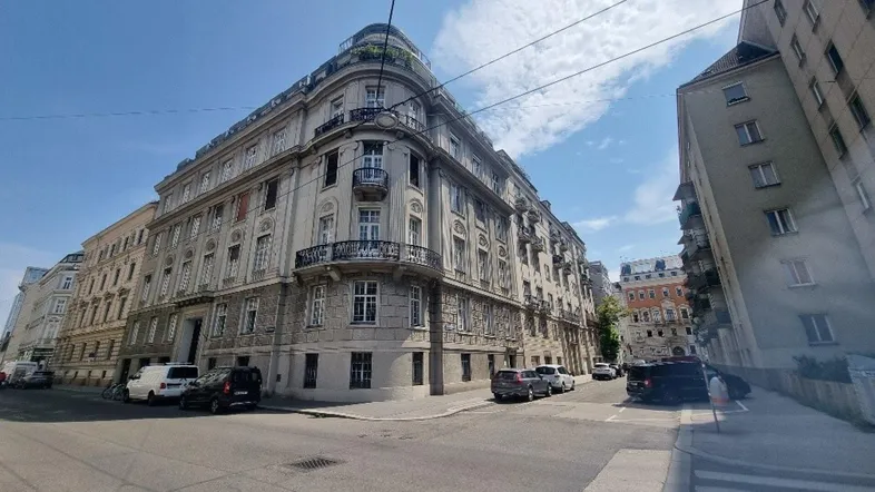 Historisches Eckgebäude mit klassischer Architektur und vielen Fenstern an einer städtischen Straße.