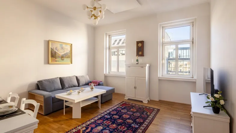 Helles Wohnzimmer mit Parkettboden, bequemer Couch, Couchtisch und einem dekorativen Teppich.
