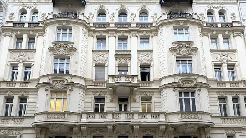 Prächtige historische Fassade eines Altbaus mit reich verzierten Balkonen und Fenstern.