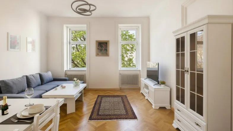 Helles Wohn- und Esszimmer mit Fischgrätparkett, bequemer Couch und Blick ins Grüne.