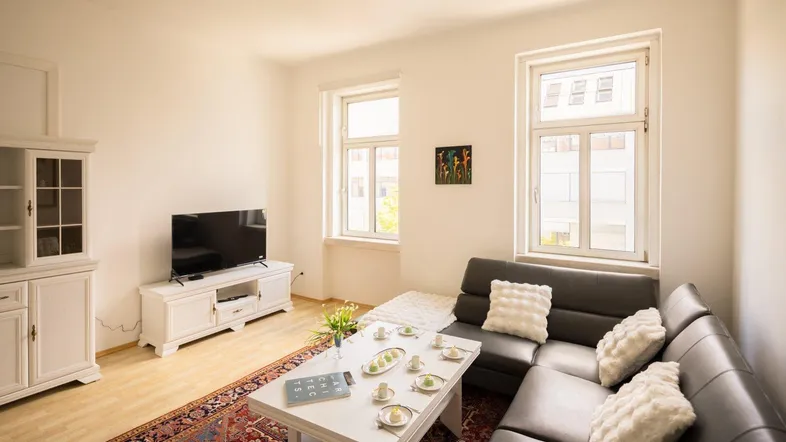 Helles Wohnzimmer mit bequemer Ledercouch, Couchtisch und TV-Möbeln auf hellem Laminatboden.