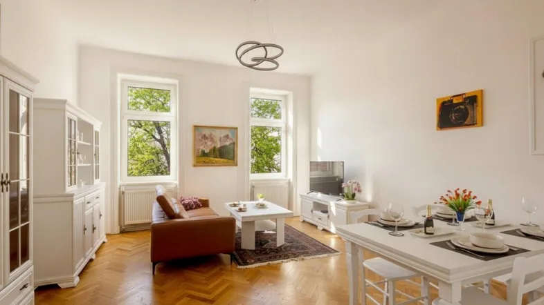 Helles Wohn- und Esszimmer mit Fischgrätparkett, weißen Möbeln und Blick ins Grüne.