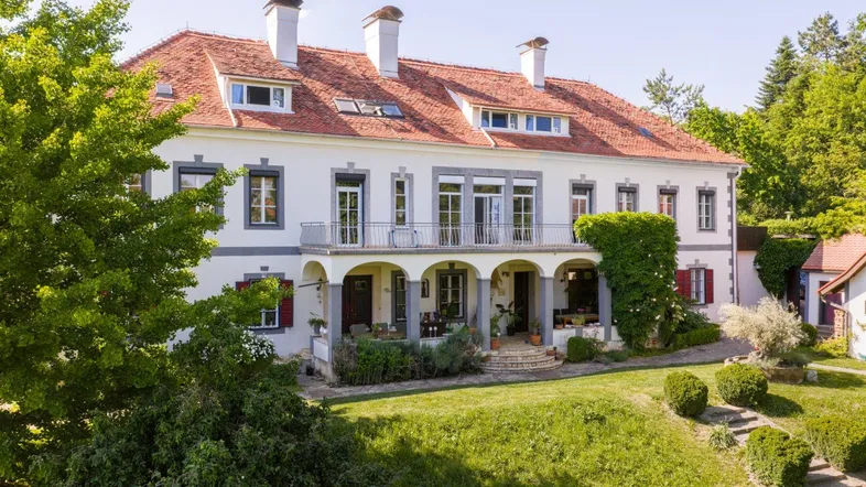 Elegante Villa mit klassischer Architektur, rotem Ziegeldach und gepflegtem Vorgarten.