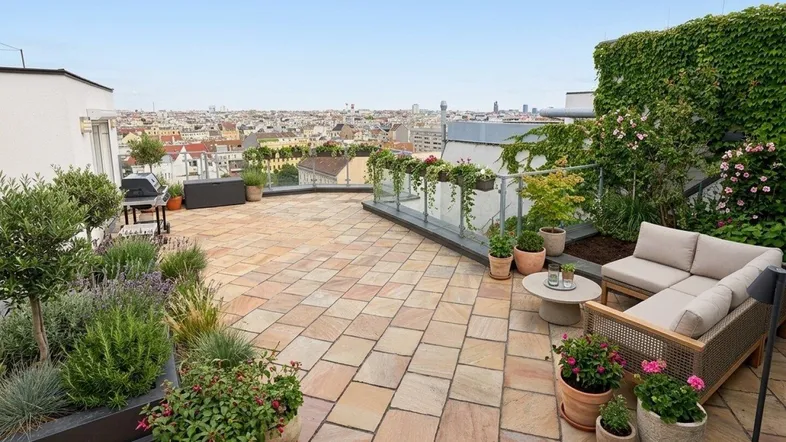 Geräumige Dachterrasse mit bequemen Sitzgelegenheiten, Pflanzen und weitem Blick über die Stadt.