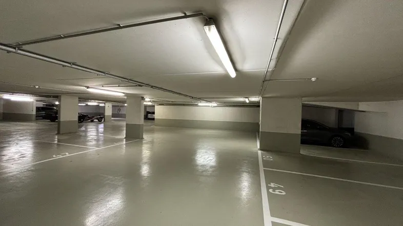 Geräumige Tiefgarage mit markierten Stellplätzen und heller Beleuchtung, die einen gepflegten Eindruck macht.