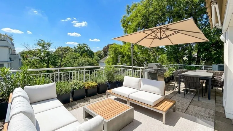 Großzügige Dachterrasse mit modernen Lounge-Möbeln, Essbereich und Grill unter blauem Himmel.