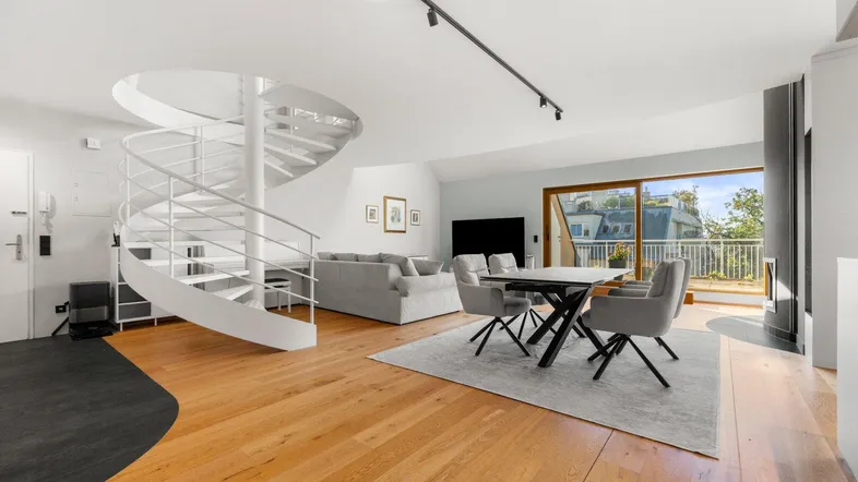 Heller Wohn- und Essbereich mit eleganter Wendeltreppe, Holzboden und Zugang zum Balkon.