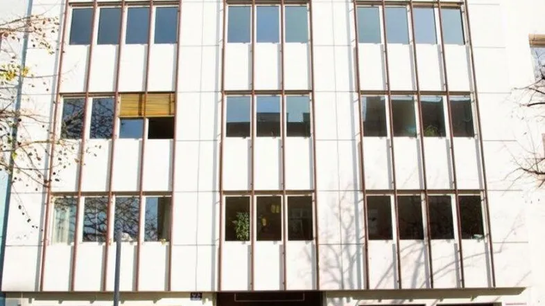 Gebäudeansicht eines modernen Büro- und Geschäftshauses mit vielen Fenstern und einer Garageneinfahrt im Erdgeschoss.