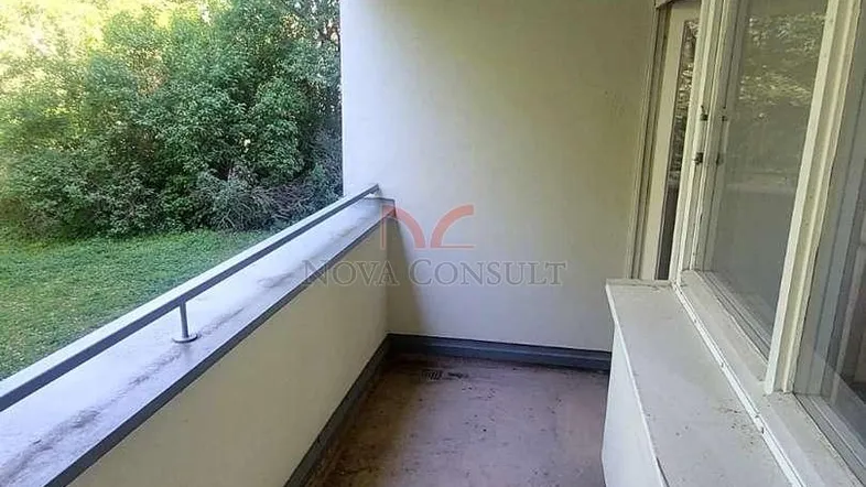 Schmaler Balkon mit Blick ins Grüne und einfacher Betonoberfläche, ideal für Entspannung.
