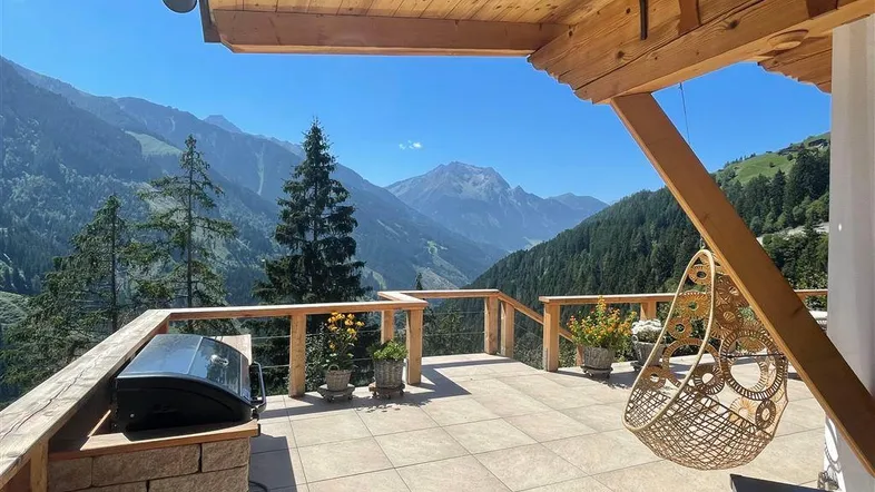 Geräumige Terrasse mit Grillbereich und atemberaubendem Bergblick, ideal für Entspannung im Freien.