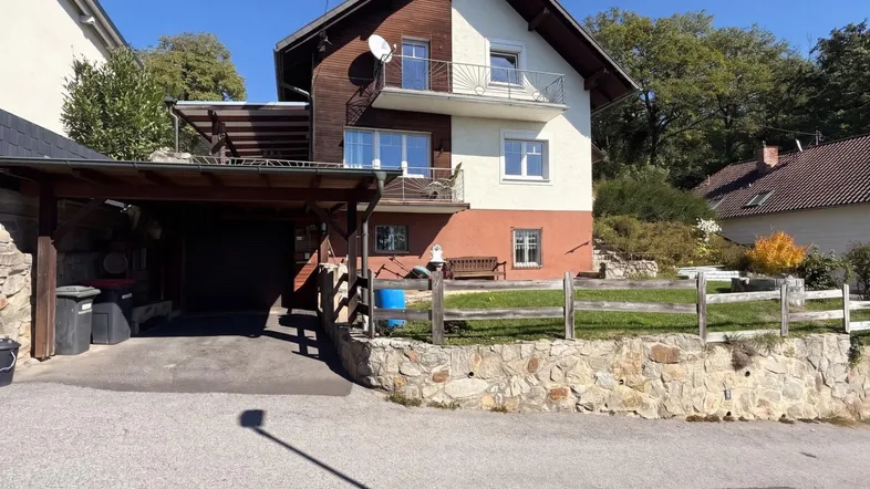 Einfamilienhaus mit Carport, Balkonen und Garten in sonniger Hanglage.