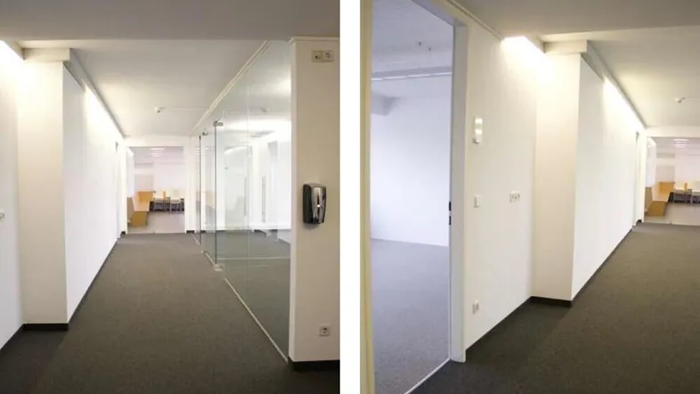 Heller Flur mit Teppichboden und Glaswänden, der zu modernen Büroräumen führt.