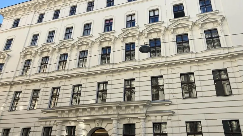 Weißes historisches Gebäude mit vielen Fenstern und dekorativen Fassadenelementen in der Rathausstraße.