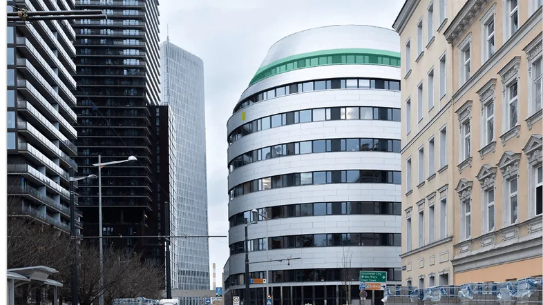 Moderne Architektur mit verschiedenen Gebäudetypen und einer geschwungenen Fassade in einer städtischen Umgebung.