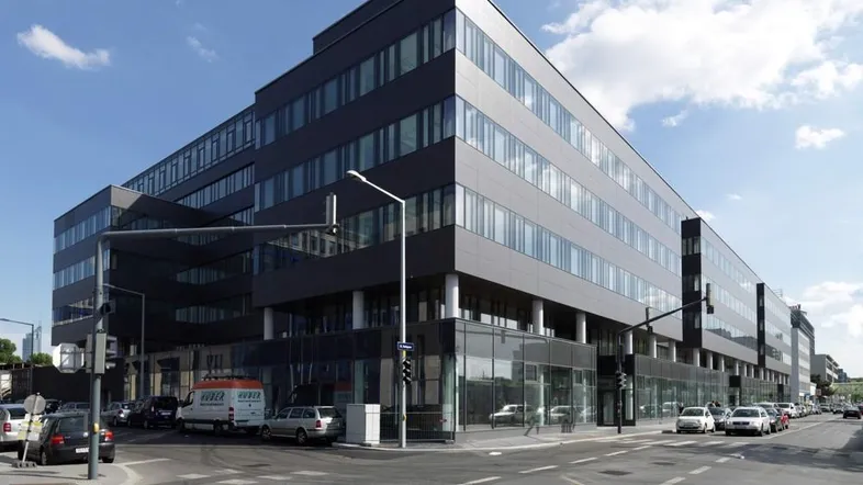 Modernes Bürogebäude mit dunkler Fassade und großen Glasflächen an einer Straßenecke.
