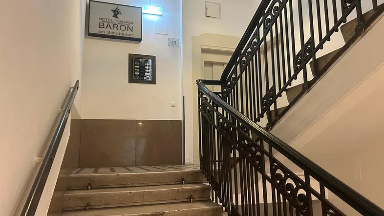 Klassisches Treppenhaus mit schmiedeeisernem Geländer und Marmorboden in einem Altbau, inklusive Aufzug.