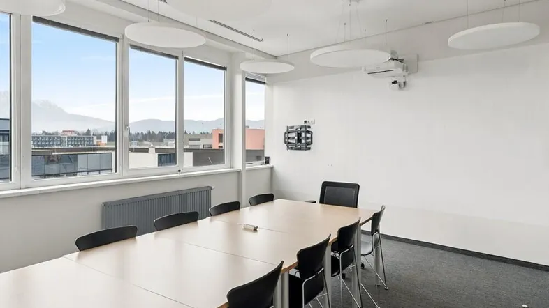 Moderner Konferenzraum mit großem Tisch, bequemen Stühlen und weitem Blick auf die Berge.