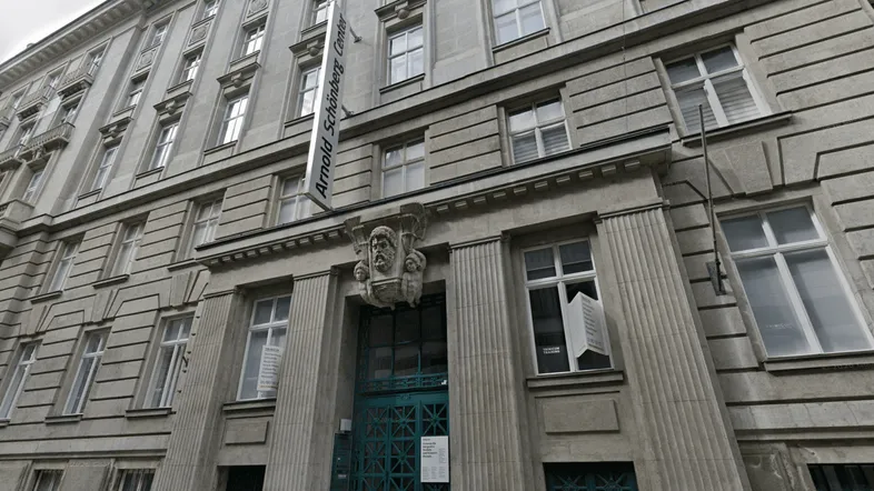 Historische Fassade eines Gebäudes mit vielen Fenstern und klassischer Architektur, inklusive Beschilderung.