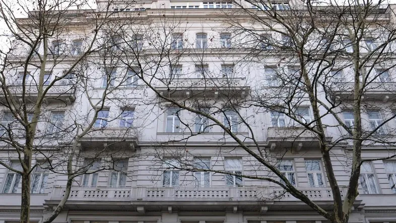 Klassisches Mehrfamilienhaus mit eleganter Fassade, vielen Fenstern und Balkonen, umgeben von kahlen Bäumen.