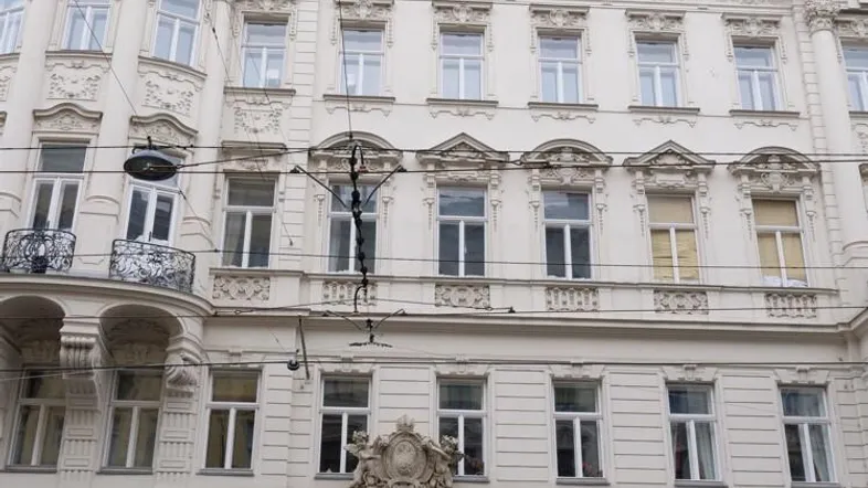 Historische Fassade eines Altbaus mit reich verzierten Details und Geschäften im Erdgeschoss.