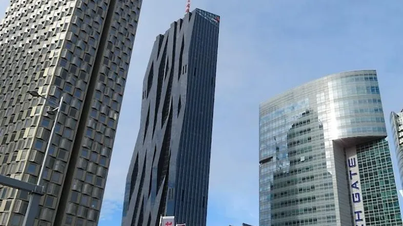 Moderne Hochhäuser mit Glasfassaden und einzigartiger Architektur unter blauem Himmel.