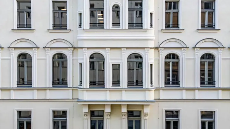 Klassische Fassade eines Altbaus mit vielen Fenstern und einem Erker in der Mitte, gut erhalten.