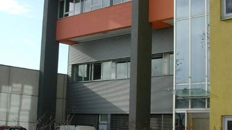 Modernes Bürogebäude mit orangefarbenen und grauen Fassadenelementen sowie großen Fenstern.