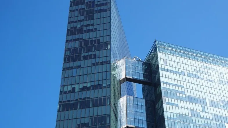 Modernes Hochhaus mit Glasfassade und klarem blauem Himmel im Hintergrund.
