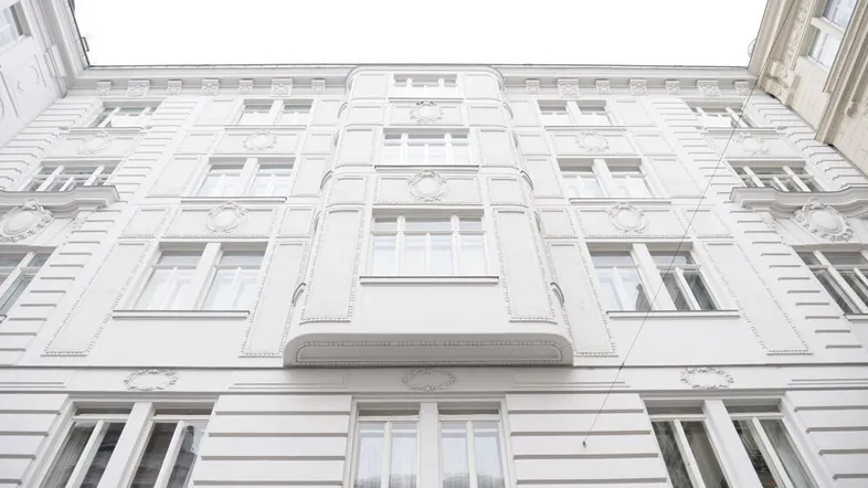 Die weiße Fassade des Gebäudes zeigt klassische Architektur mit dekorativen Elementen und vielen Fenstern.